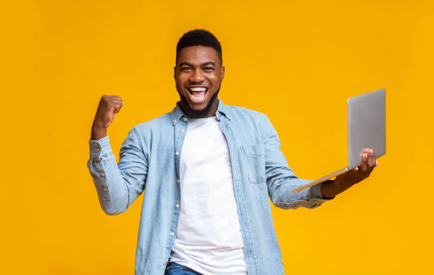 istock Happy black guy rejoicing success with laptop 1187799683
