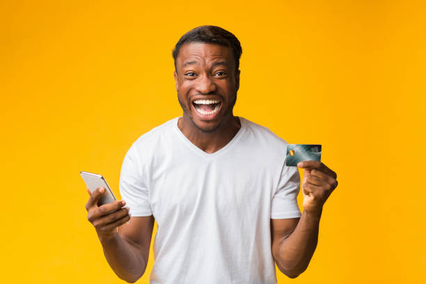 istock Happy Man Holding Smartphone And Credit Card Standing, Studio Shot 1187799772