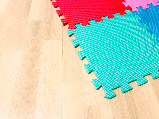 Soft rubber mat composed of colored blocks intersected with each other on a wooden floor
