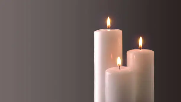 Three white candles burning on gray gradient background. Front view. Horizontal composition