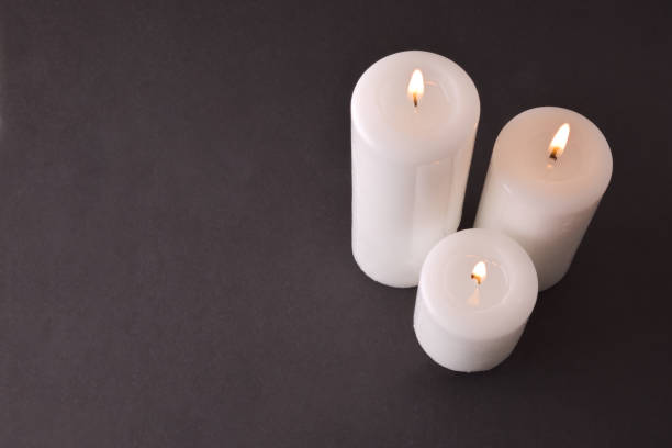 istock Three burning candles on gray degrading background top view 1187801216