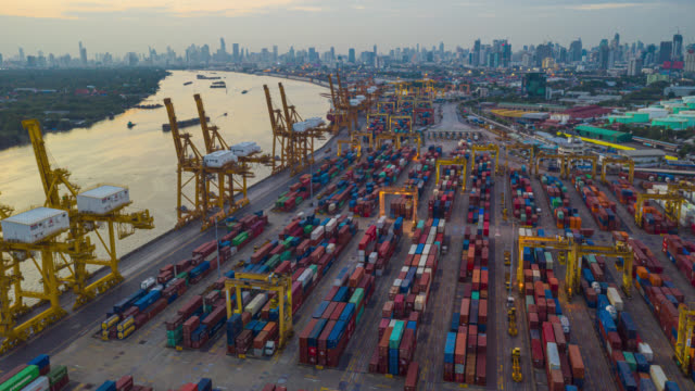 Hyperlapse or Dronelapse aerial view of international port with Crane loading containers in import export business logistics.