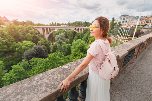 Happy Asian girl stands on the balcony of the observation deck in the Grand Duchy of Luxembourg. Tourism and travel in Europe