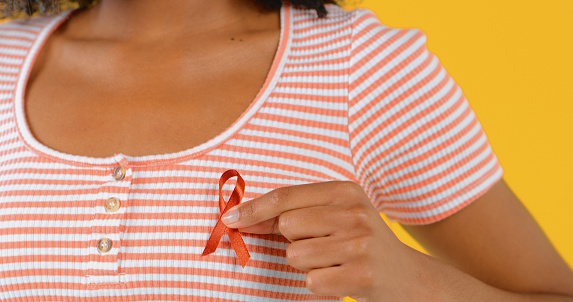 Studio shot of an unrecognizable woman holding up a red HIV/AIDS awareness ribbon