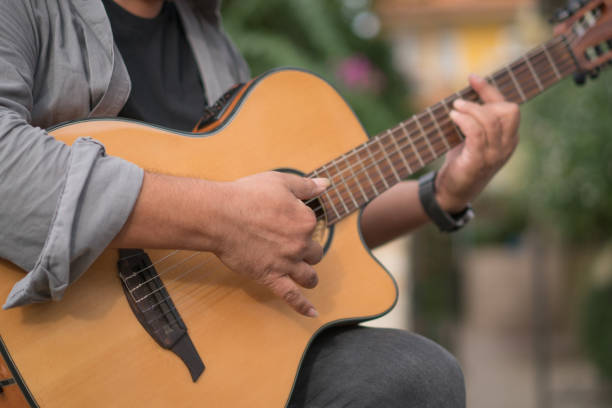 istock Mid adult man playing guitar close up 1187805964
