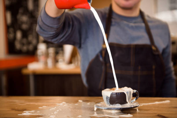 Close up barista pouring too much milk in coffee cup, making latte art