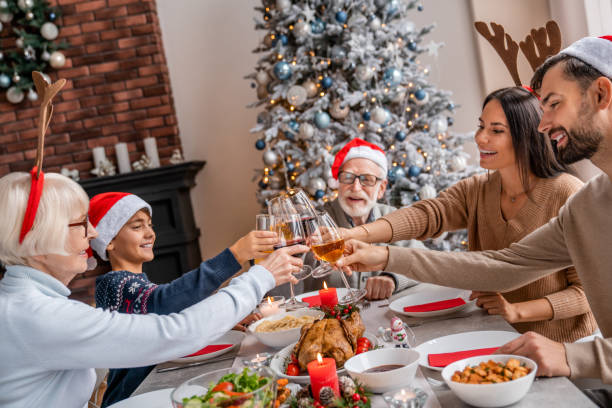 familia de tres generaciones disfrutando y tosando vino en la cena de navidad - los niños y los padres brindis bebidas mientras almuerza fotografías e imágenes de stock