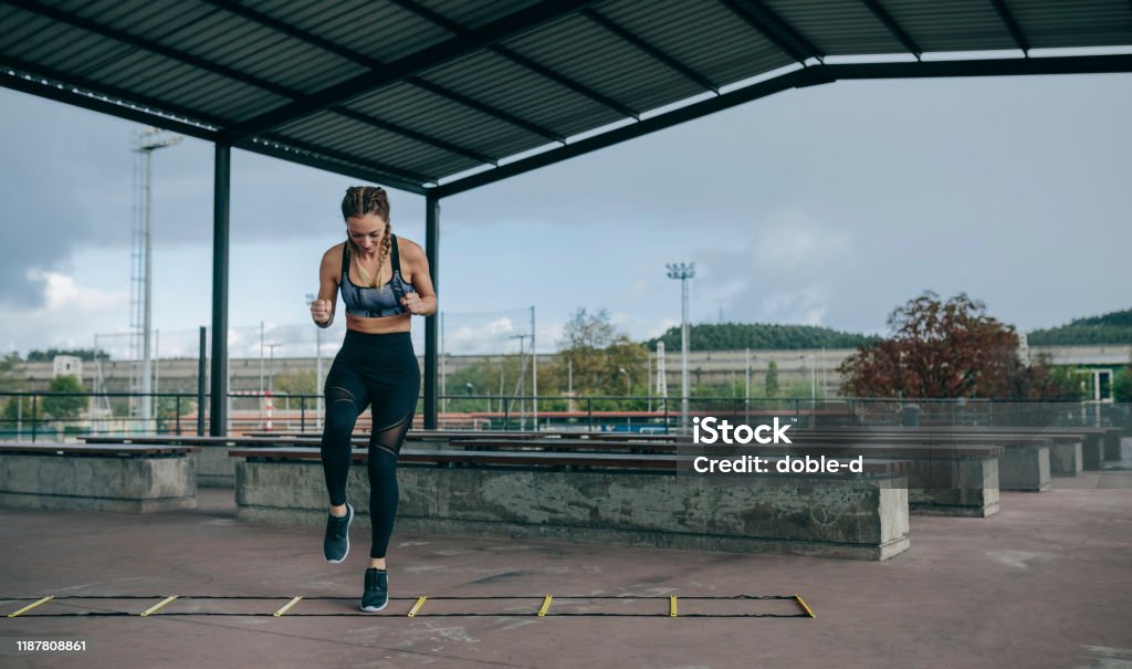 Sportlerin springt auf einer Agilitätsleiter - Lizenzfrei Leiter Stock-Foto