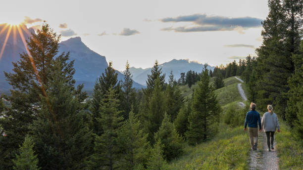 成熟したカップルは日の出でトレイルを歩く - dawn mountain range mountain canadian rockies ストックフォトと画像