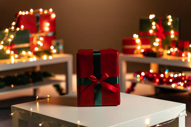 istock Red Christmas present on white table, defocused Christmas lights in background, bokeh 1187813451