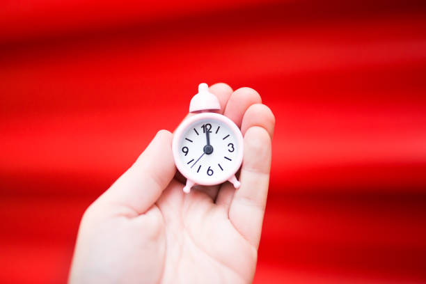 istock Alarm clock in hand on red background 1187817984