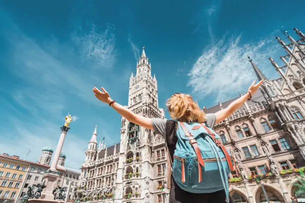 Photo of A girl tourist traveler enjoys a Grand view of the Gothic building of the Old town Hall in Munich. Sightseeing and exploration of Germany concept