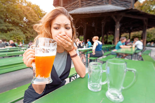 une fille essaye une bière avec une expression de dégoût dans un bar de rue. concept d'intoxication à l'alcool et cesser de boire - intoxication photos et images de collection