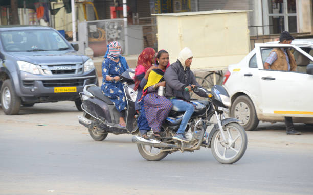 A dynamic shot capturing two motorcycle riders in motion, speeding through a bustling urban street at dusk. The image features a blurred motion effect, emphasizing the fast-paced nature of city transport. The riders are wearing protective helmets and jackets, highlighting the importance of safety while commuting. This photo encapsulates the vibrancy and energy of city life, with the road illuminated by the fading light and vehicle headlights.
