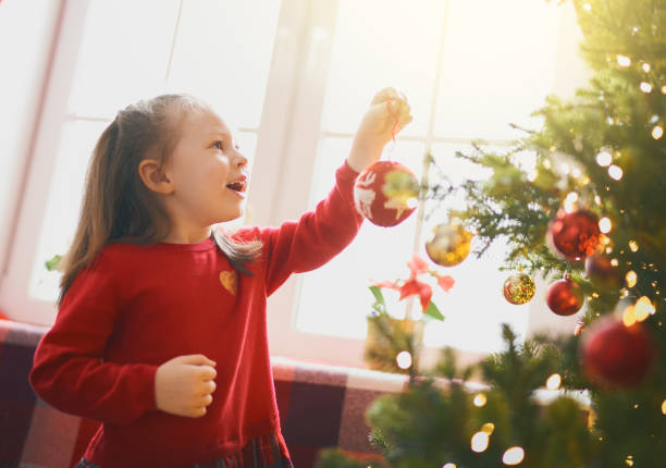 istock child with baubles near tree at home. 1187822067