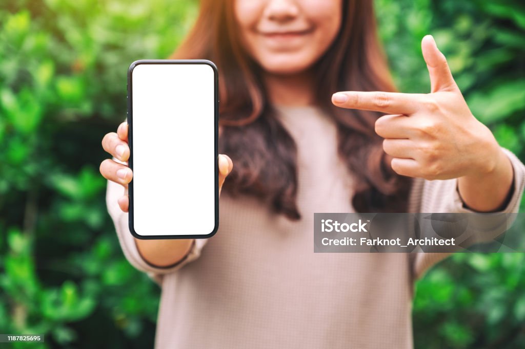 a woman holding and pointing finger at a black mobile phone with blank desktop screen in the outdoors - Royalty-free Apontar - Sinal Manual Foto de stock