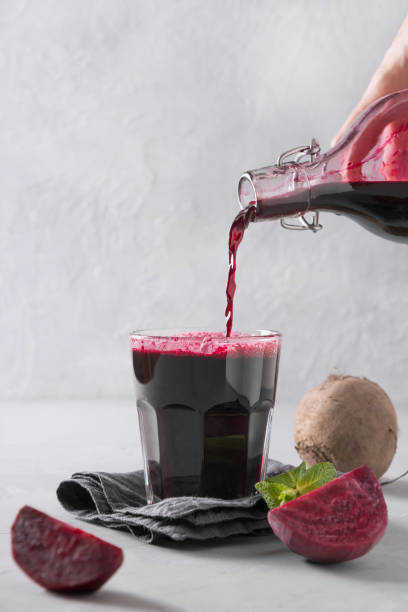 istock Pour beetroot juice from bottle in glass. Close up. Vertical orientation. 1187827089