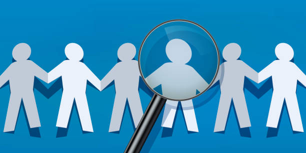 istock Recruitment symbolized by paper characters who hold hands and are scrutinized. 1187827193