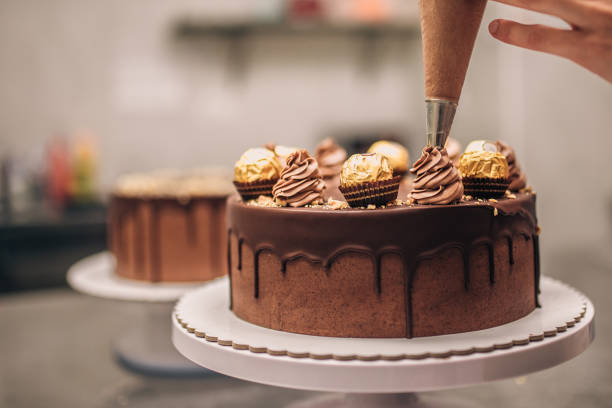 confeiteiro decorando bolo de chocolate, close-up. - bolo sobremesa - fotografias e filmes do acervo