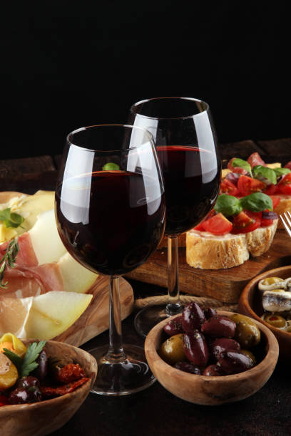 italian antipasti wine snacks set. cheese variety, mediterranean olives, seafood salad, prosciutto di parma, tomatoes, anchovy and wine in glasses - bruschetta buffet party food imagens e fotografias de stock