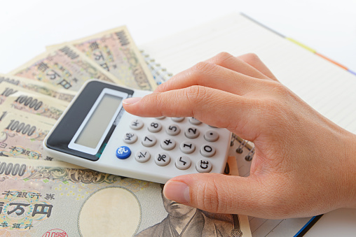 Woman counting money and working on calculator at the table