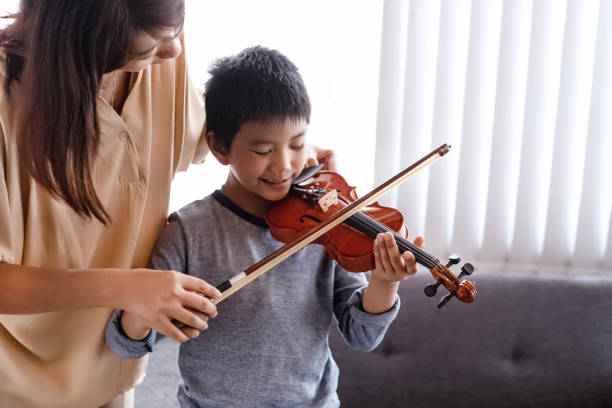 istock Teacher teaching young boy for playing violin,music class,at studio,withhappy feeling,blurry light around 1187842799