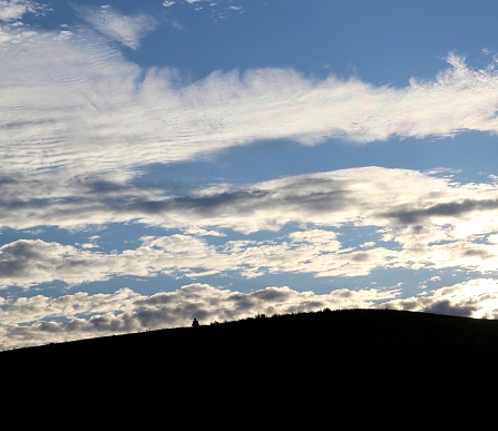 The clouds in the sun setting sky with the silhouette of the hill in the foreground.