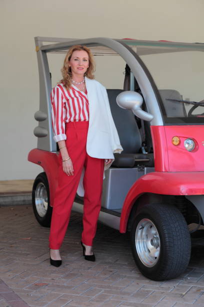 femme dans la tenue rouge sur l'avant du chariot de golf - golf cart golf mode of transport transportation photos et images de collection
