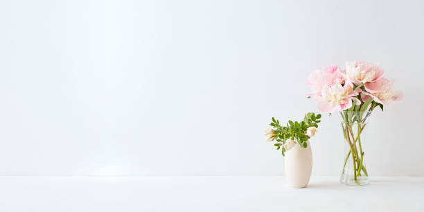 istock Home interior with decor elements. Pink peonies in a vase and white flowers on a white background 1187845245