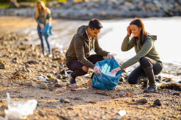 team of volunteers collecting garbage at beach - group of people women beach community imagens e fotografias de stock