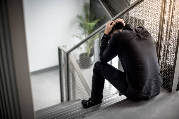 Asian man feeling stressed sitting on stair Asian businessman feeling stressed and headache sitting on stair in office building. Depression from business problem. Mental health illness or office syndrome concept struggle stock pictures, royalty-free photos & images