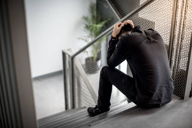 asian man feeling stressed sitting on stair - struggle imagens e fotografias de stock