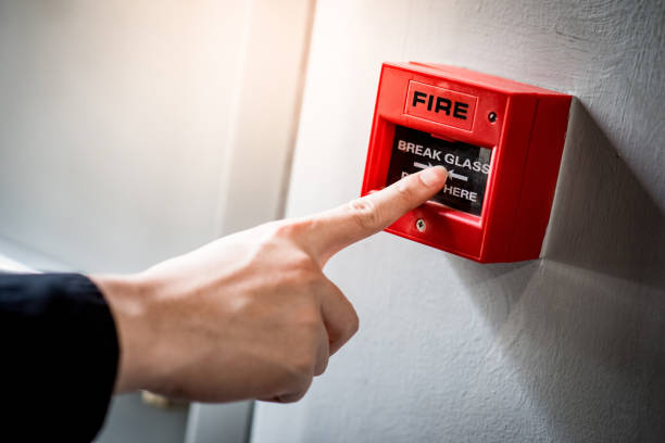 Male hand pointing at red fire alarm switch stock photo