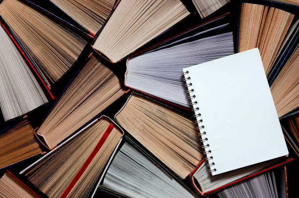 istock A white notebook with clean pages rests on old multicolored books 1187848276
