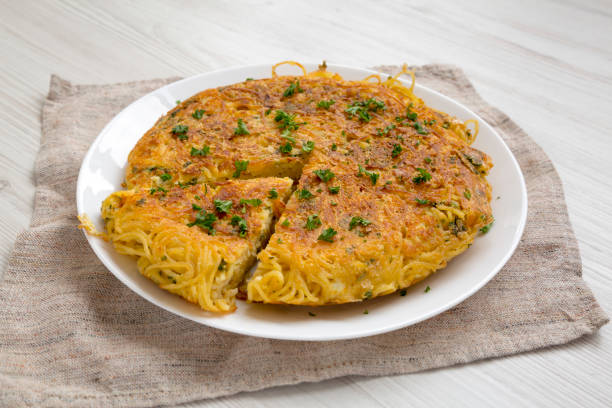 Homemade spaghetti omelette on a white plate, side view. Close-up. Homemade spaghetti omelette on a white plate, side view. Close-up. frittata stock pictures, royalty-free photos & images