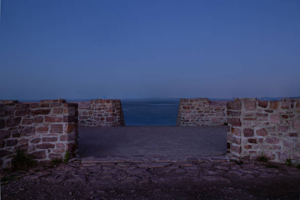 Some little wall of rocks creating a gate to see the sea in the background during blue hour.