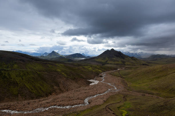 Dramatic Iceland landscape with green mountains covered with thick Icelandic moss and river on a gray moody cloudy day. Iceland adventure hiking Laugavegur trail to Landmannalaugar.