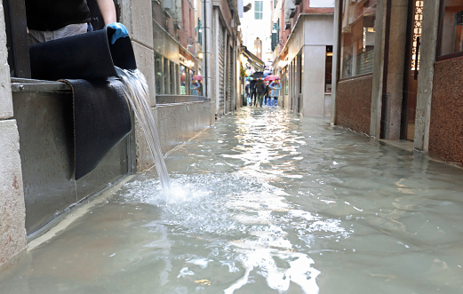 Street of Venice called CALLE in Italian language with high water and a bucket to empty the store