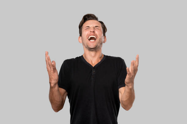 istock Angry man in a black tee shouting isolated over grey background. 1187864669