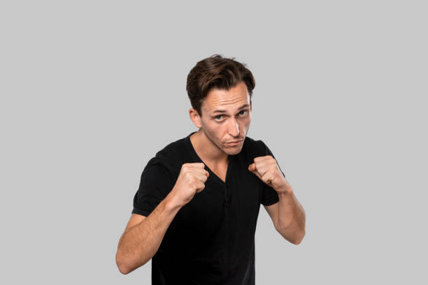istock Man ready to fight standing in a boxing pose isolated over grey background. 1187864675
