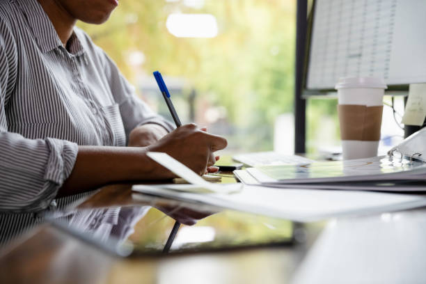 istock Businesswoman writes note at her desk 1187865884