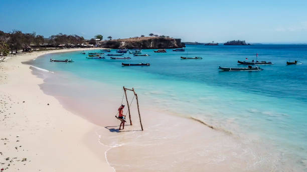 lombok - un uomo che oscilla su un'altalena di legno in riva al mare - flores man foto e immagini stock