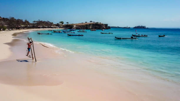 lombok - un uomo che oscilla su un'altalena di legno in riva al mare - flores man foto e immagini stock