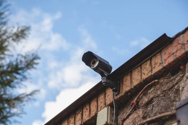 istock Surveillance video camera on background of blue sky 1187867044