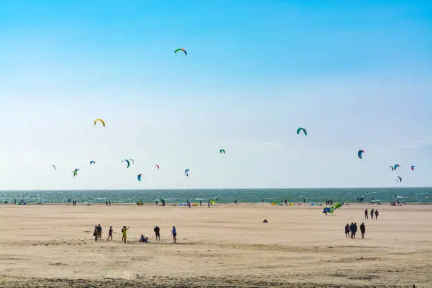 Water sport event, colorful kite surfers race in North Sea near Renesse, Zeeland, Netherlands