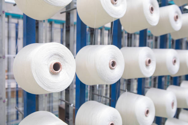 istock Group of bobbin thread cones on a warping machine in a textile mill. Yarn ball making in a textile industry factory. 1187867949