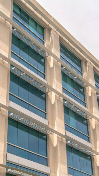 istock Vertical frame Modern building facade close up with glass windows and sunlit concrete wall 1187868085