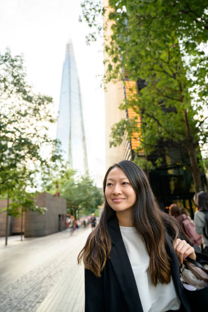 Contented Chinese businesswoman taking a break in London Close-up of relaxed young Chinese businesswoman in London enjoying a break outdoors with Shard London Bridge in background. the shard close up stock pictures, royalty-free photos & images