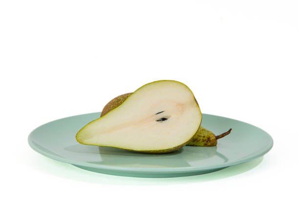 istock Conference pear cut in half on a green plate 1187872637