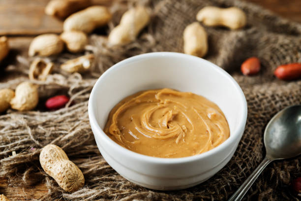 istock Peanut butter with peanuts on a dark wood background 1187872709